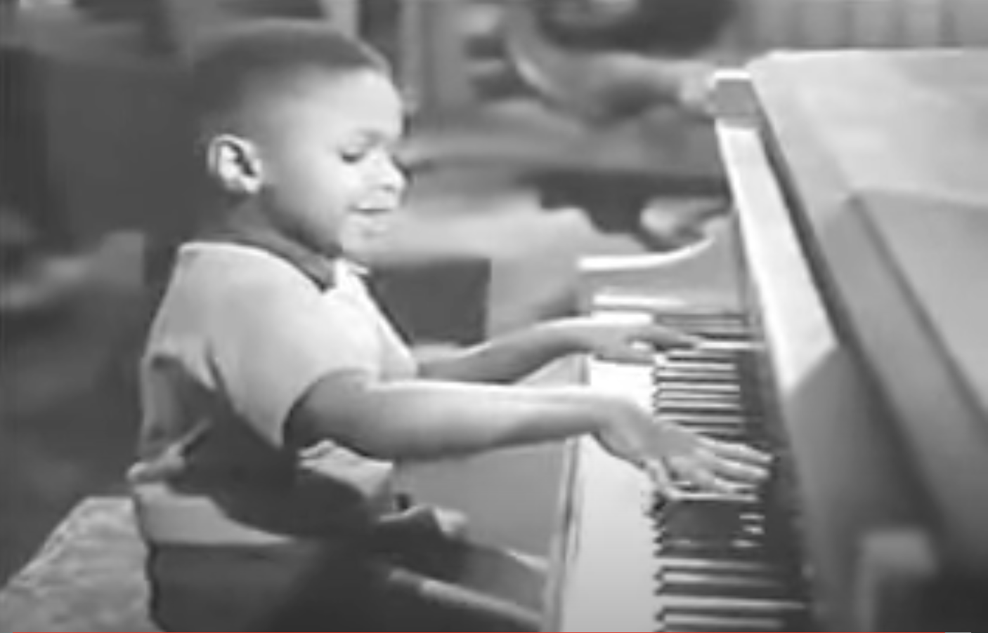 Young Sugar Chile Robinson smiling while playing the keyboard