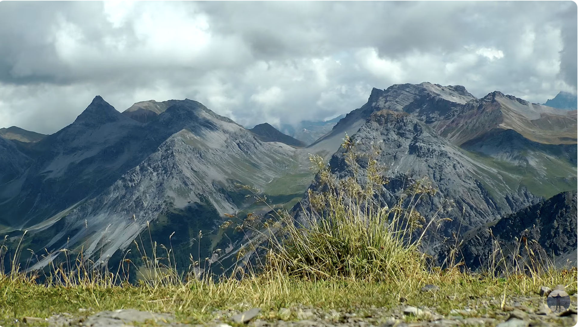 Swiss mountains with grass/scrub in front. Cloudy. Silent wind.